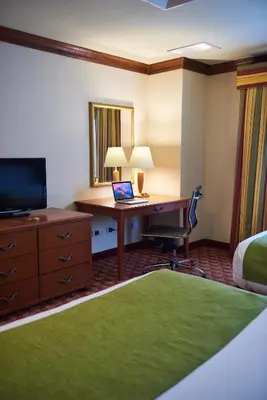a hotel room with a desk and a bed and a computer at Suites las Palmas, Hotel & Apartments. in San Salvador