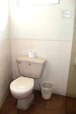 a bathroom with a toilet with a roll of toilet paper on it at Ximenas Guest House in San Salvador