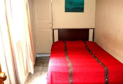 a red bed in a room with a window at Ximenas Guest House in San Salvador