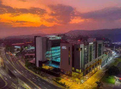 a city with buildings and a street at sunset at Hyatt Centric San Salvador in San Salvador