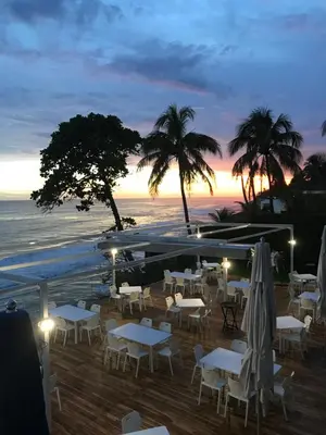a restaurant with white tables and chairs and the ocean at Acantilados in La Libertad