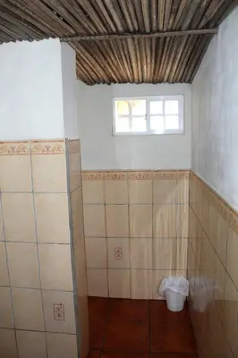 a bathroom with tiled walls and a window at Capricho Beach House in El Zapote