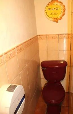 a bathroom with a red toilet and a toaster at Capricho Beach House in El Zapote