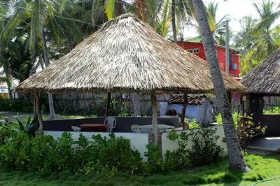 a hut with a straw roof and chairs and palm trees at Capricho Beach House in El Zapote