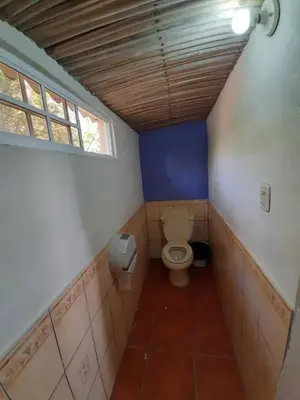 a bathroom with a toilet and a window at Capricho Beach House in El Zapote
