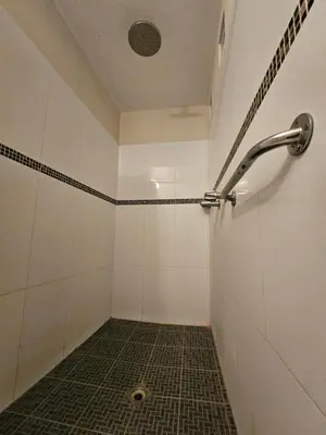 a bathroom with a shower with a tiled floor at Hotel San Jose Hostal in San Salvador