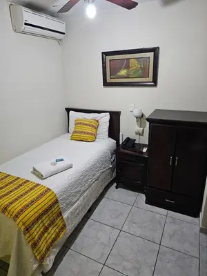 a bedroom with a bed and a dresser with a yellow blanket at Hotel San Jose Hostal in San Salvador