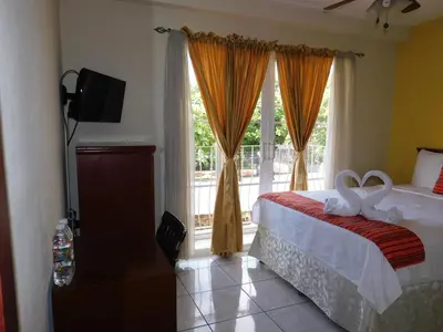 a bedroom with a bed and a large window at Hotel San Jose Hostal in San Salvador