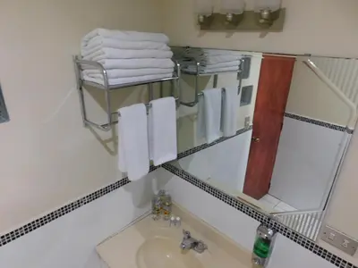 a bathroom with a sink and a mirror and towels at Hotel San Jose Hostal in San Salvador