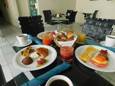 a table with two plates of breakfast foods and drinks at Hotel San Jose Hostal in San Salvador
