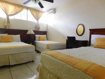 a hotel room with two beds and a mirror at Hotel San Jose Hostal in San Salvador