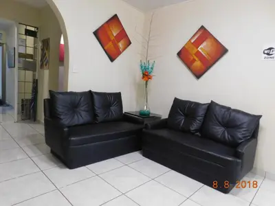 two black leather couches in a room with paintings on the wall at Hotel San Jose Hostal in San Salvador