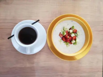 a bowl of oatmeal with fruit and a cup of coffee at Hotel Citlalli in San Salvador