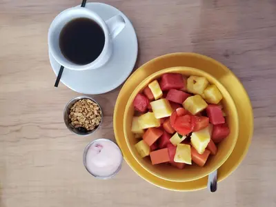 a bowl of fruit next to a cup of coffee at Hotel Citlalli in San Salvador