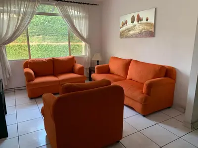 a living room with two orange couches and a window at Zona Rosa San Benito 1 cuartito in San Salvador