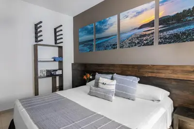 a bedroom with a bed with four paintings on the wall at Palo Verde Sustainable Hotel in El Zonte