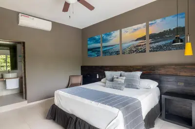 a bedroom with a bed with four paintings on the wall at Palo Verde Sustainable Hotel in El Zonte