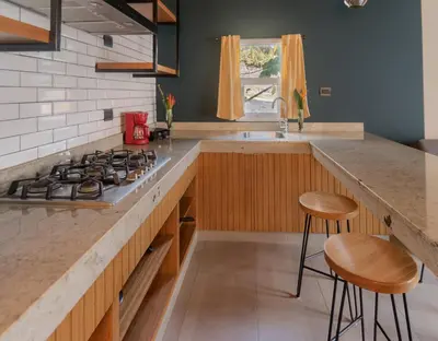 a kitchen with a stove and a counter with stools at Palo Verde Sustainable Hotel in El Zonte