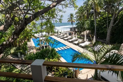 an outdoor swimming pool with lounge chairs and the beach at Palo Verde Sustainable Hotel in El Zonte