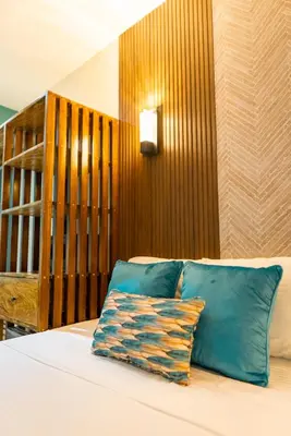 a bed with blue pillows and a wooden wall at Mar & Sol, Hotel y resturante in La Unión