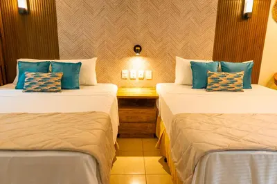 two beds in a hotel room with blue pillows at Mar & Sol, Hotel y resturante in La Unión