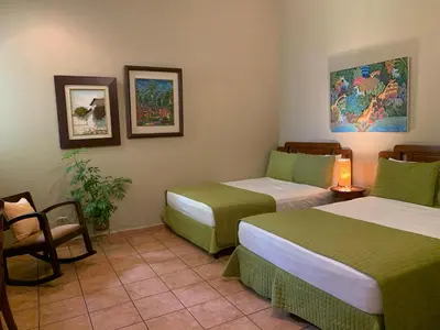 a hotel room with two beds and a chair at Hotel La Posada del Angel in San Salvador