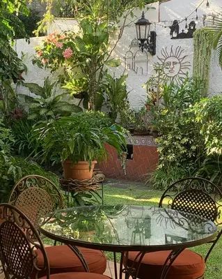 a patio with a table and chairs and plants at Hotel La Posada del Angel in San Salvador