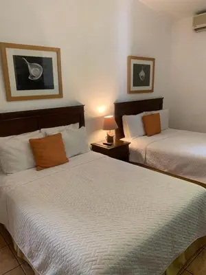 a bedroom with two beds and a lamp on a table at Hotel La Posada del Angel in San Salvador