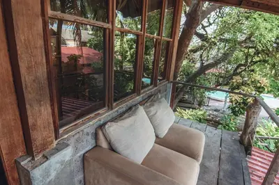 a couch with pillows sitting on a balcony at Esencia Nativa in El Zonte