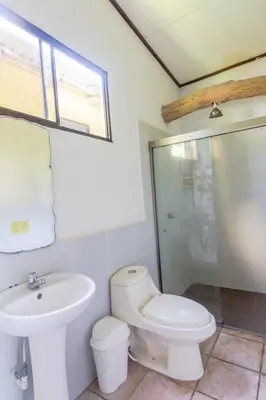 a white bathroom with a toilet and a sink at Esencia Nativa in El Zonte
