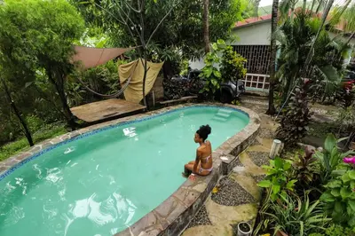 a woman sitting in a swimming pool at Casa de Colores in El Zonte