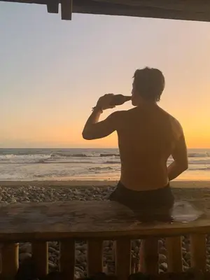 a man sitting on a bench looking at the ocean at Pelicano Surf Camp in La Libertad