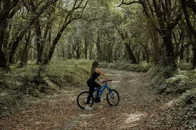 a woman riding a bike on a forest trail at Hotel Finca Campo Bello in Cerro Verde