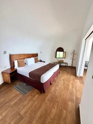 a bedroom with a large bed and a wooden floor at Hotel Finca Campo Bello in Cerro Verde