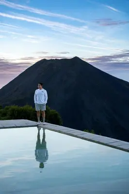 a man standing on the edge of a pool with a mountain at Hotel Finca Campo Bello in Cerro Verde
