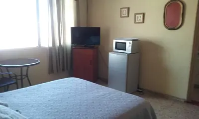 a bedroom with a television and a microwave on a refrigerator at Casa San Benito in San Salvador
