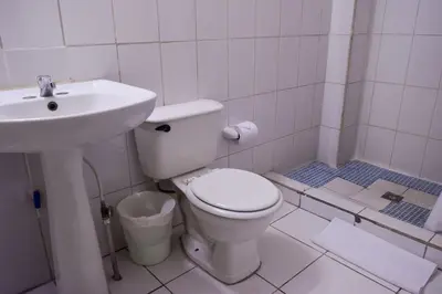 a white bathroom with a toilet and a sink at Hotel San José de la Montaña in San Salvador