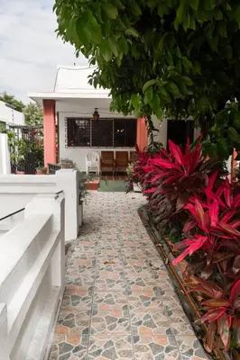 a walkway leading to a house with red plants at Hotel San José de la Montaña in San Salvador