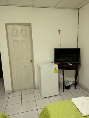 a room with a refrigerator and a television and a table at Hotel San José de la Montaña in San Salvador