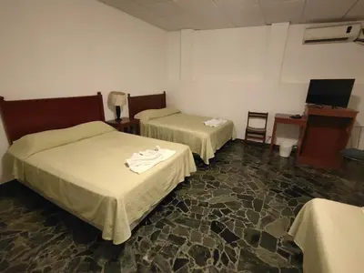 a room with two beds and a desk and a computer at Hotel San José de la Montaña in San Salvador