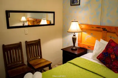 a bedroom with a bed and a mirror and a chair at Hostal Koltin Suchitoto in Suchitoto