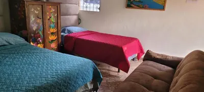 a bedroom with two beds and a table with a red blanket at HOSTAL CABAÑAS AVE MARIA in Concepción de Ataco