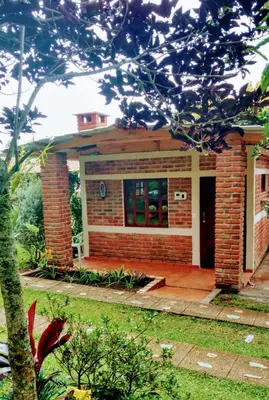 a small brick house with a front porch at HOSTAL CABAÑAS AVE MARIA in Concepción de Ataco