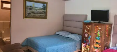 a small bedroom with a bed and a tv at HOSTAL CABAÑAS AVE MARIA in Concepción de Ataco