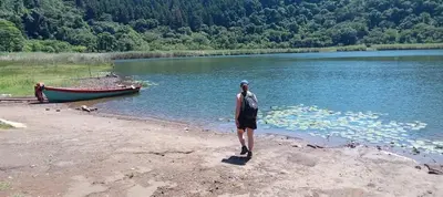 a man standing on the shore of a lake with a boat at Hostal Doña Mercedes in Juayúa
