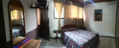 a bedroom with two beds and a mirror at Hostal Doña Mercedes in Juayúa