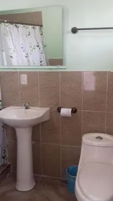 a bathroom with a sink and a toilet and a mirror at Hostal Doña Marta in San Salvador