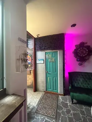 a room with a green door and a purple wall at Velvet Hostal La novena in Santa Ana