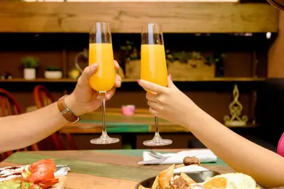 two people are holding up glasses of orange juice at Velvet Hostal La novena in Santa Ana