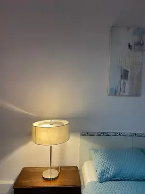 a lamp on a table next to a bed at Velvet Hostal La novena in Santa Ana